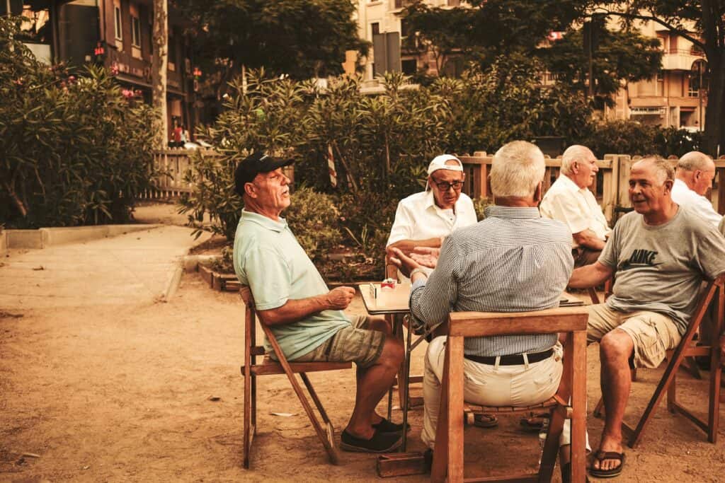 A group of senior citizen men sitting around a table outside. Photo by Cristina Gottardi on Unsplash.