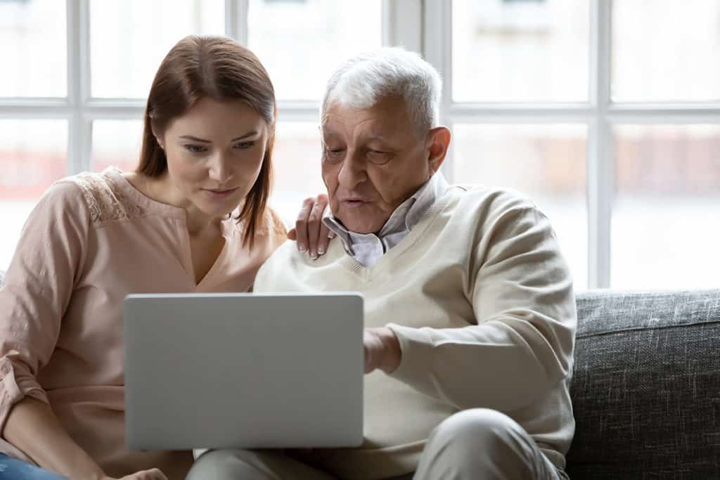 A senior man with his daughter looking at assisted living options on a laptop