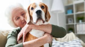 A senior woman smiling and hugging a cute dog